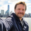 Smiling man taking selfie with city skyline