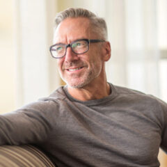 Smiling middle-aged man with glasses on sofa
