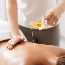 Therapist pouring massage oil onto client's back