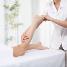 Therapist performing leg massage on treatment table